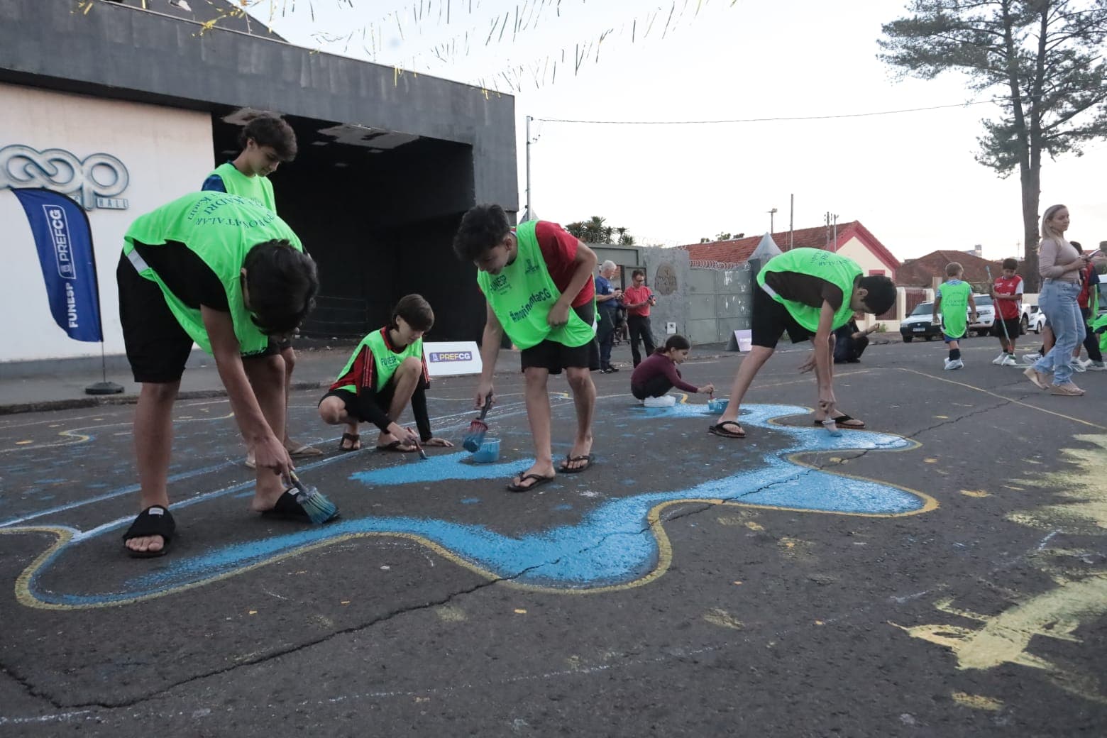 Alunos de escolinha de futebol ajudam a pintar rua da Cidade da Copa